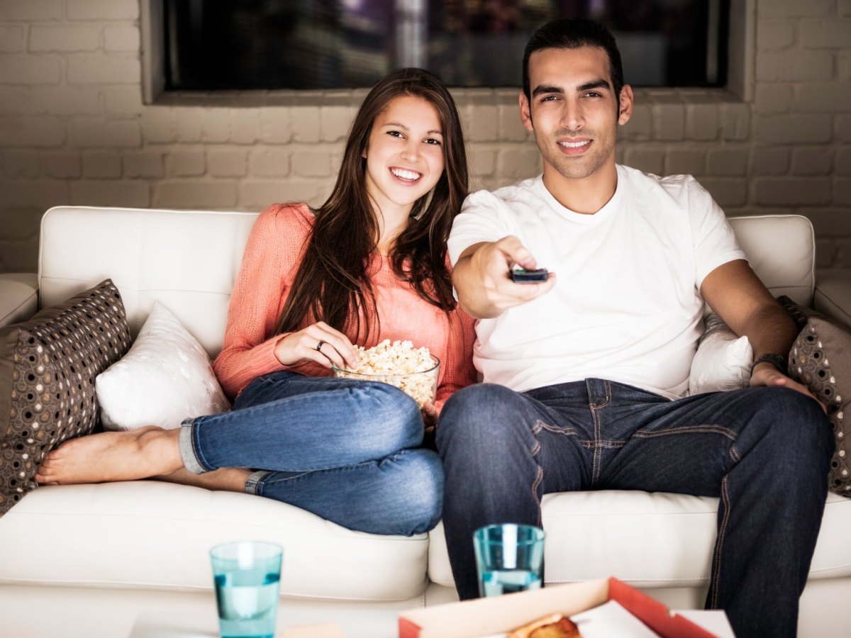 Mann und Frau mit Popcorn auf der Couch.