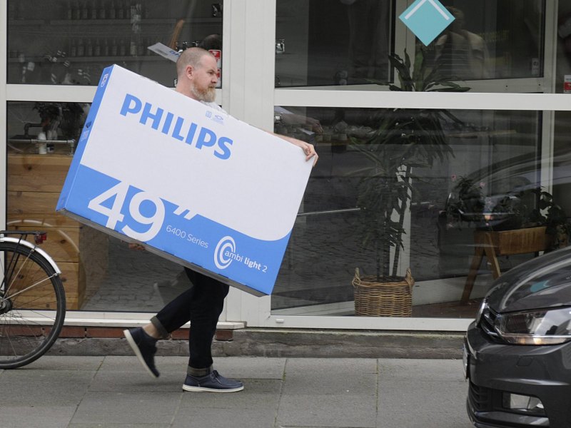 Mann trägt Paket mit Philips Smart TV