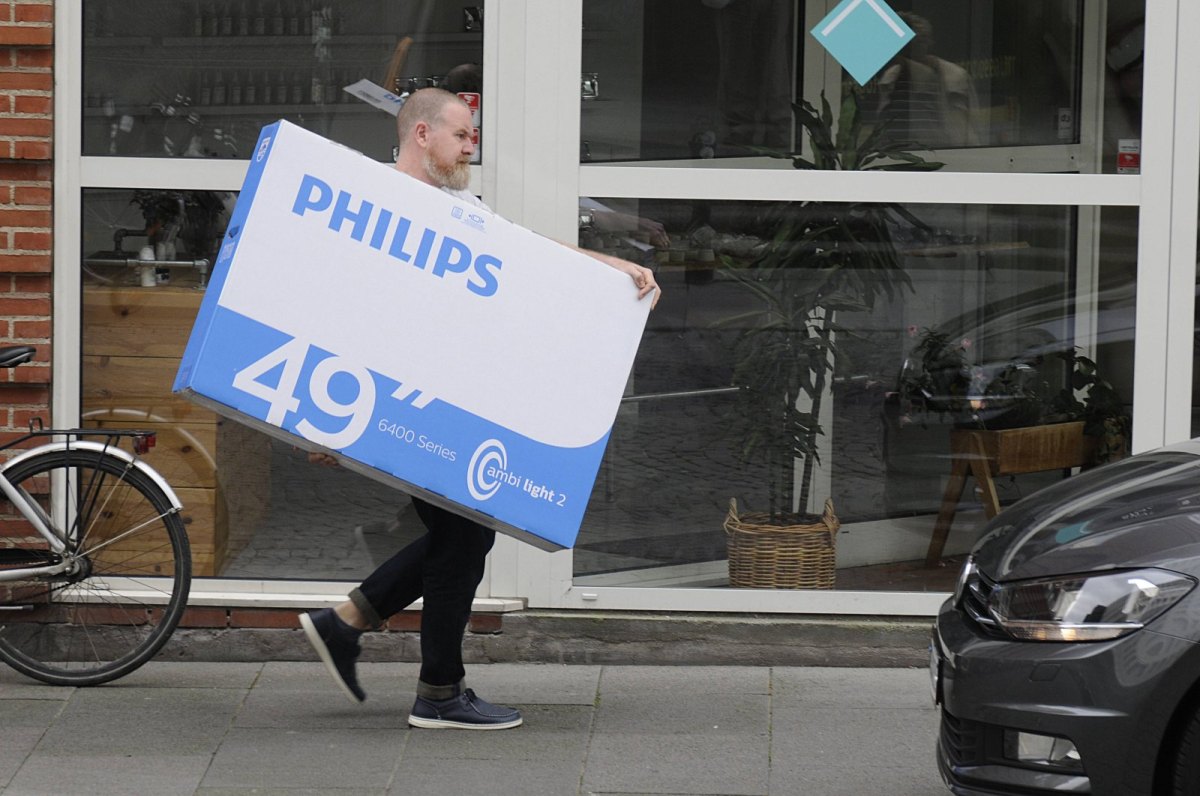 Mann trägt Paket mit Philips Smart TV
