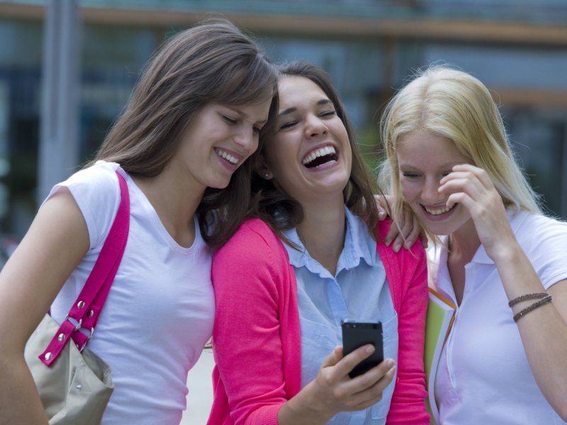 Drei junge Frauen mit Smartphone lachend