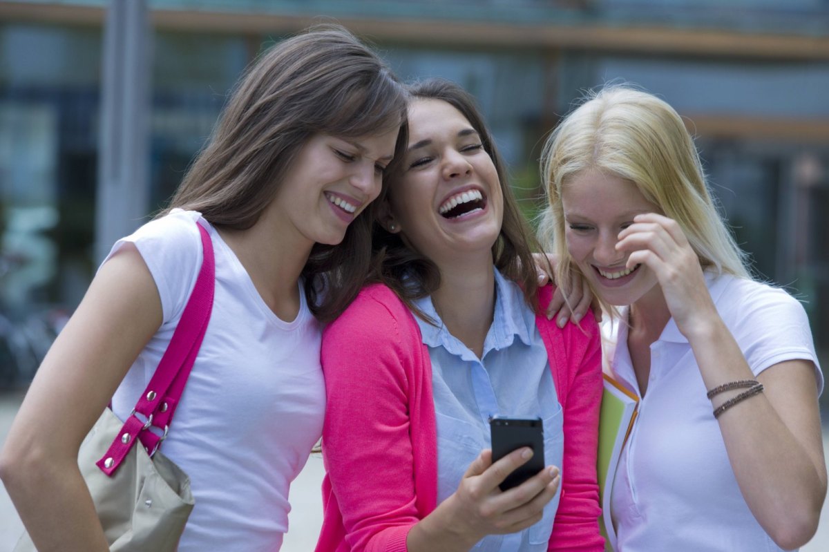 Drei junge Frauen mit Smartphone lachend