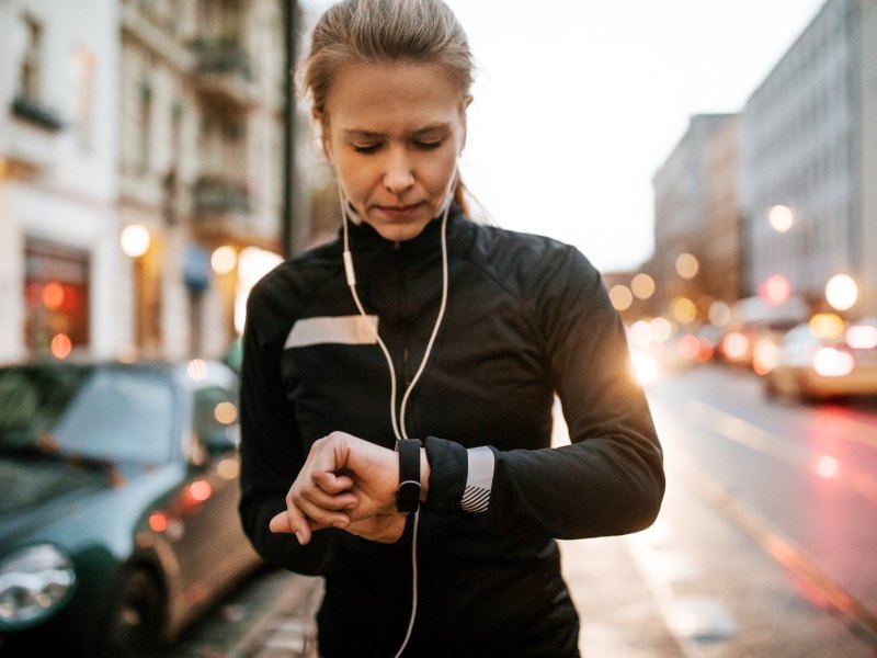 Frau mit Smartwatch und Kopfhörern auf der Straße.