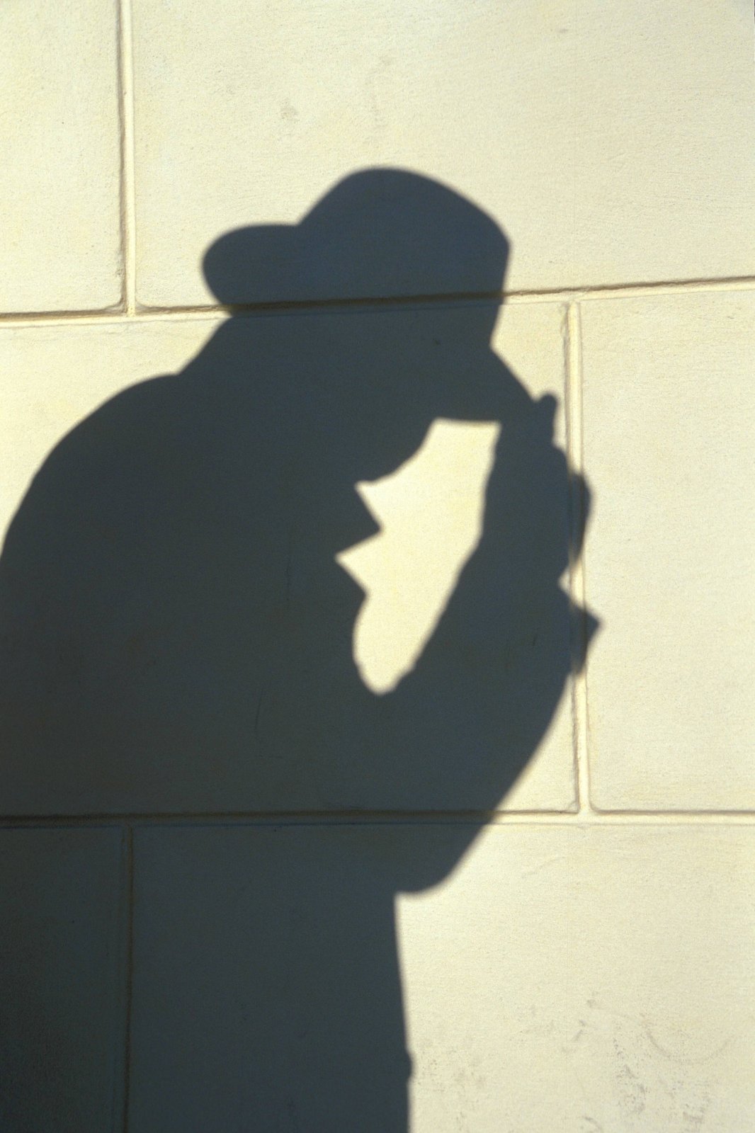 Der Schatten einer Person mit Mantel und Hut