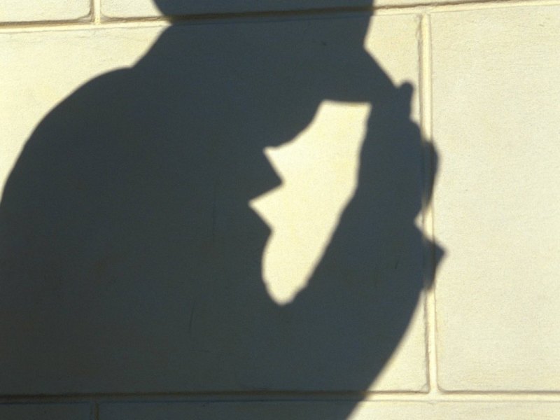 Der Schatten einer Person mit Mantel und Hut