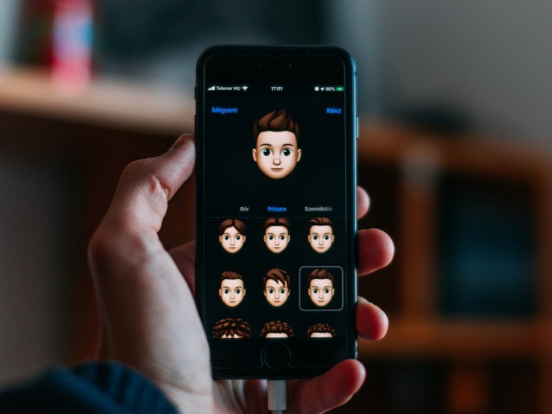 Eine Hand mit einem iPhone auf dem man Memojis sieht.