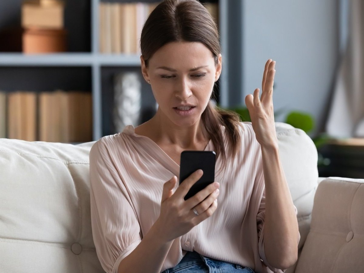 Frau regt sich am Handy auf.