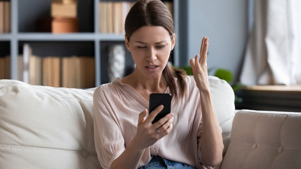 Frau regt sich am Handy auf.