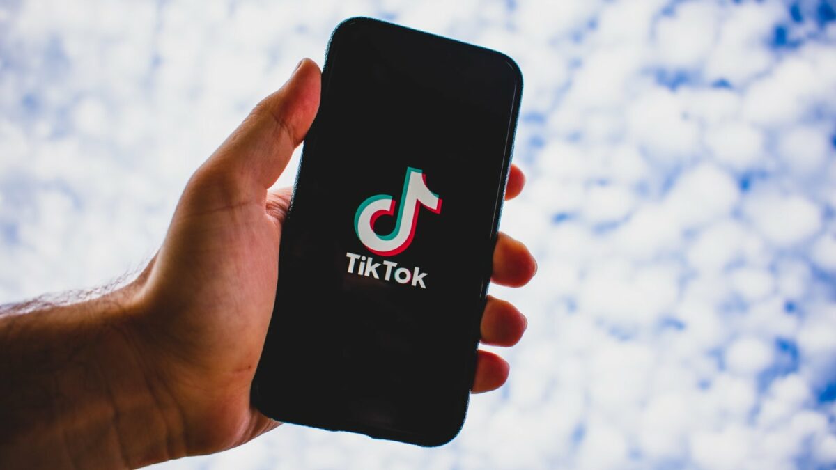 Eine Hand mit einem Smartphone auf dem das TikTok-Logo zu sehen ist.