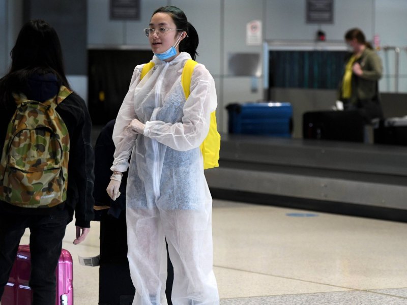 Frau in Schutzanzug am Flughafen