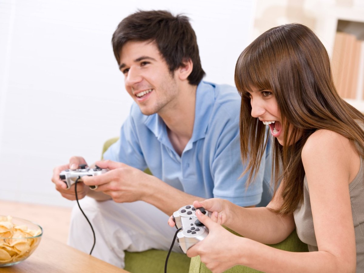 Mann und Frau spielen gemeinsam ein Videospiel mit Controllern in der Hand
