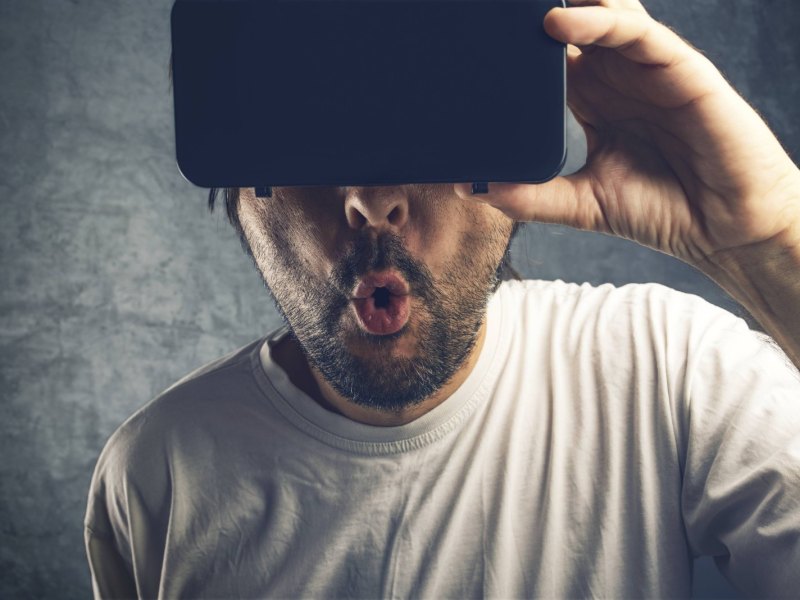 Mann staunt mit VR-Headset auf dem Kopf.