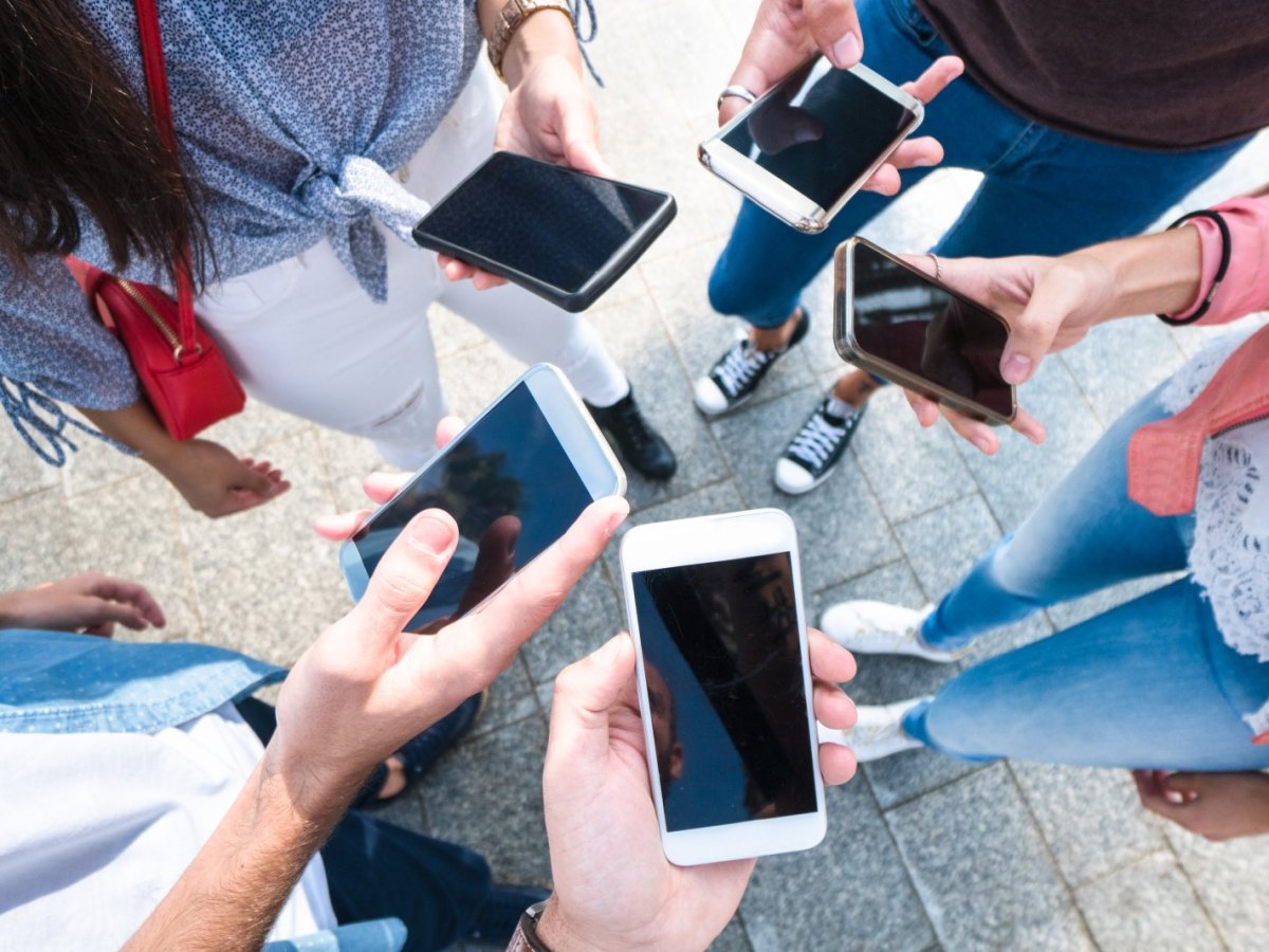 Menschenhände mit verschiedenen iPhones in der Hand.
