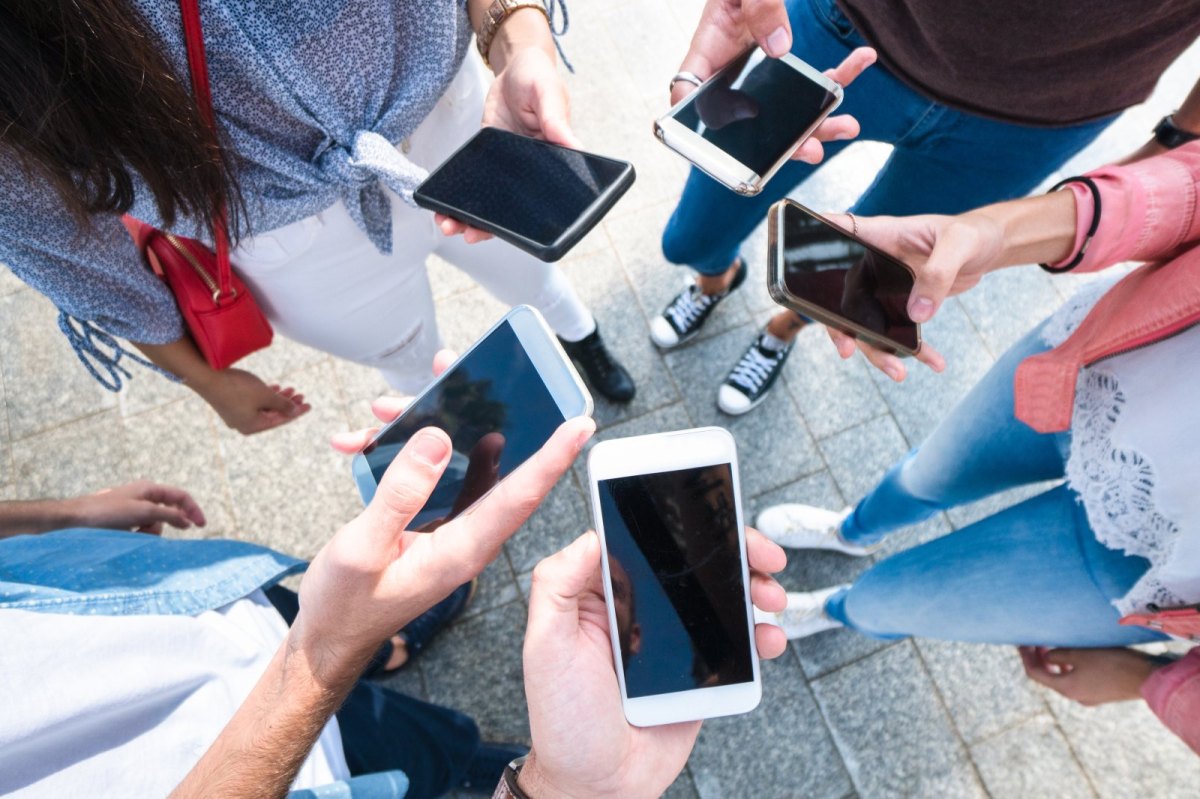 Menschenhände mit verschiedenen iPhones in der Hand.