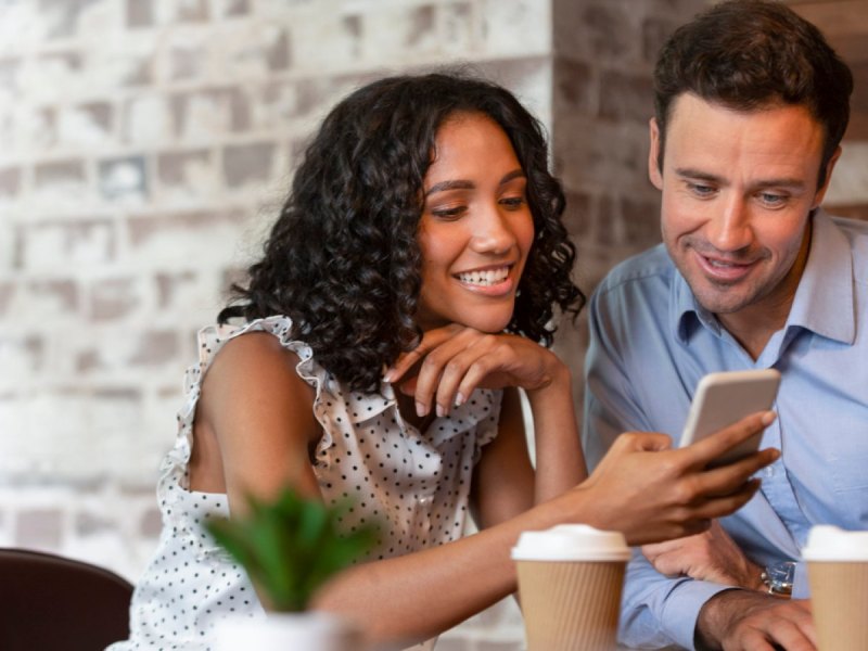 Frau und Mann blicken auf ein Handy.