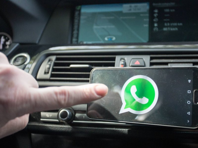 Ein Finger nähert sich einem WhatsApp-Icon auf einem Handy.