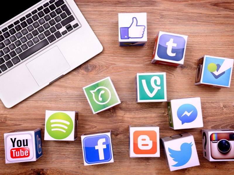 Macbook und verschiedene Logos von Social Media-Plattformen