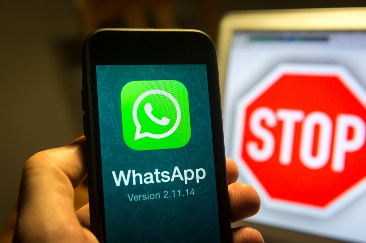 WhatsApp auf dem Handy und ein Stoppschild im Hintergrund
