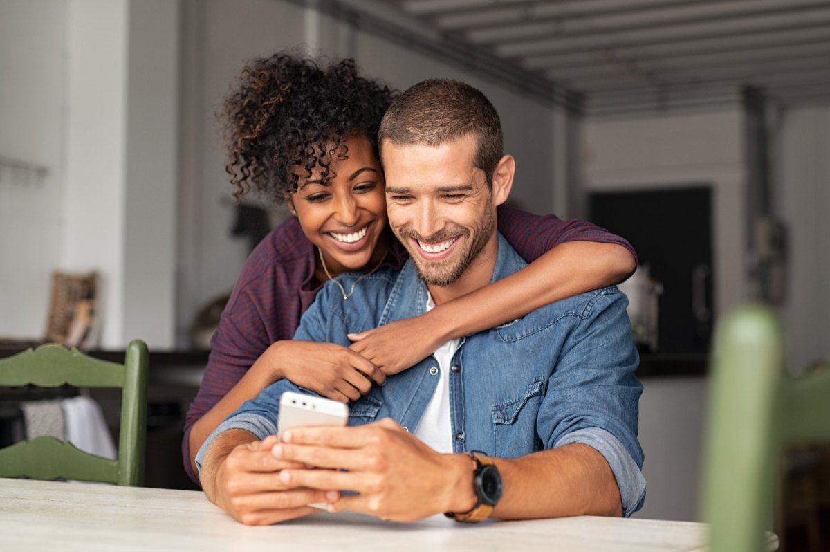 Ein Mann und eine Frau blicken glücklich auf ein Handy.