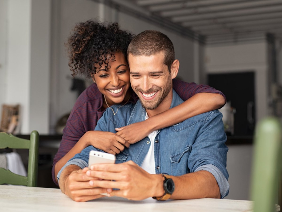 Ein Mann und eine Frau blicken glücklich auf ein Handy.