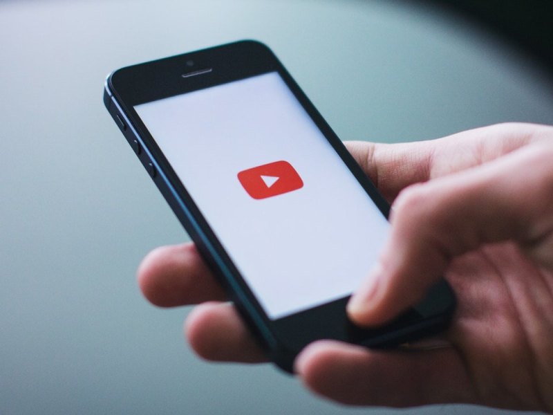 Ein Smartphone mit YouTube-Logo in einer Hand.