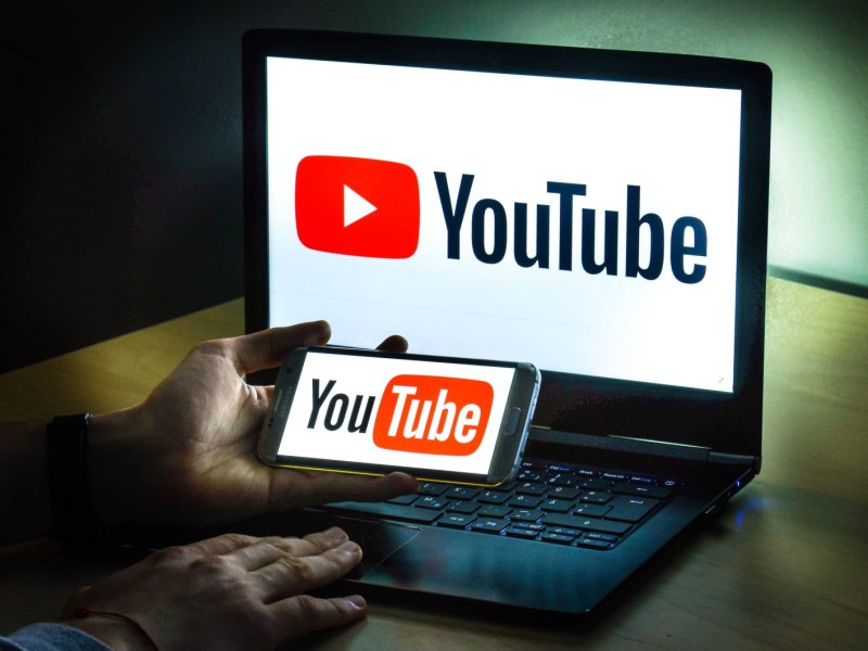 Auf einem Laptop und einem Smartphone ist das YouTube-Logo zu sehen.