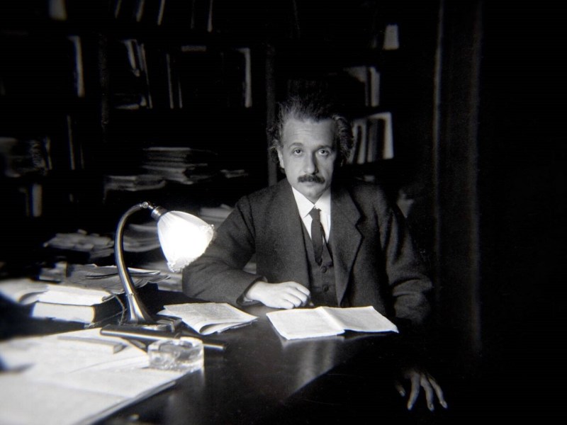 Einstein am Schreibtisch sitzend
