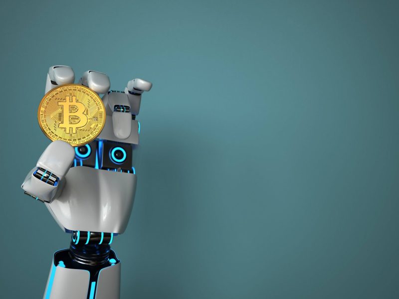Roboterhand hält einen Bitcoin