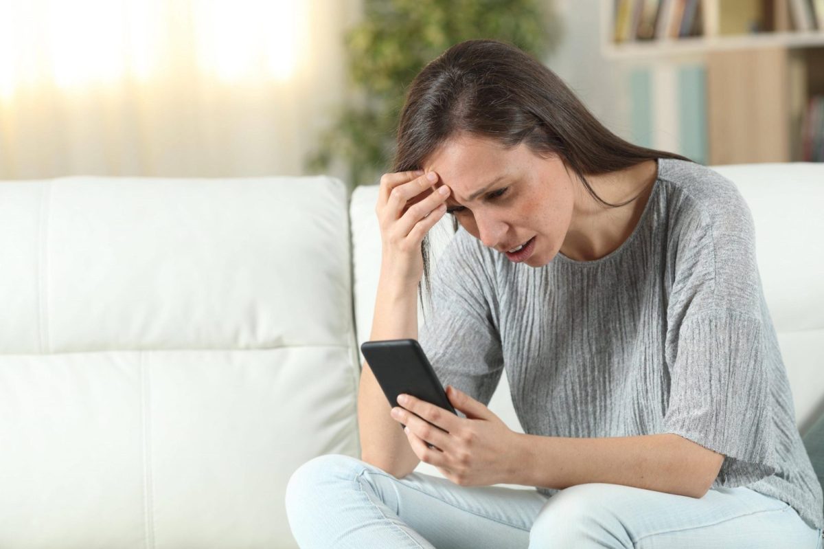 Frau schaut besorgt auf Smartphone