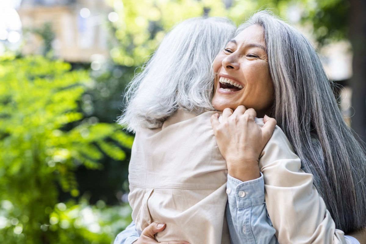 Zwei Frauen mit grauen Haaren umarmen sich
