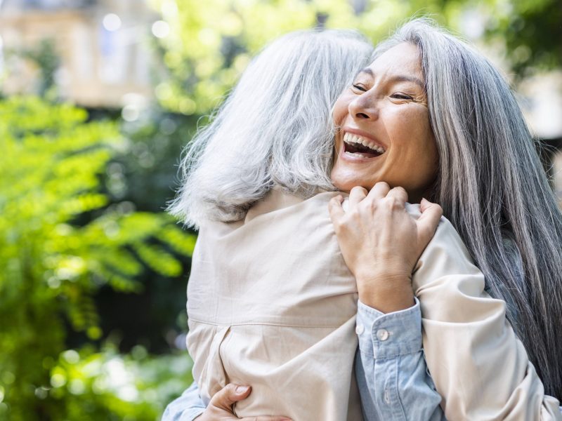 Zwei Frauen mit grauen Haaren umarmen sich