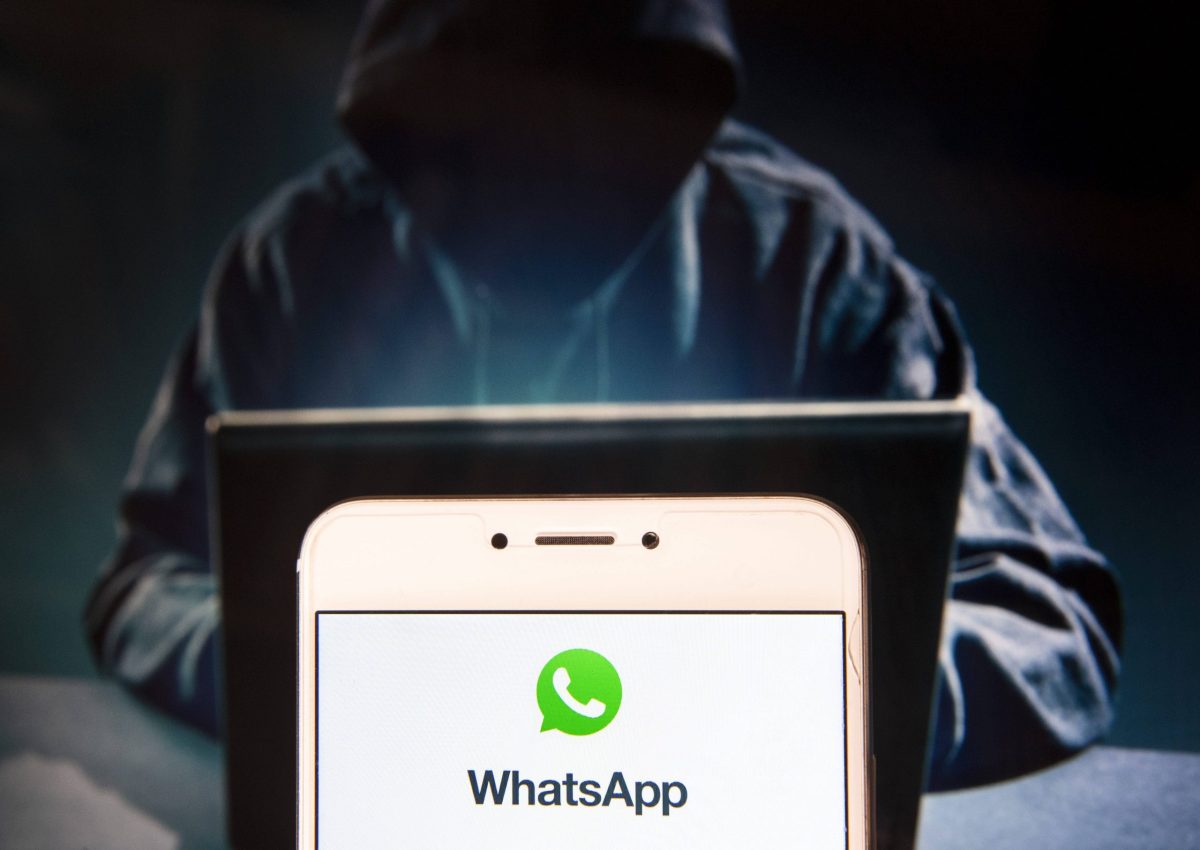 Hacker hinter WhatsApp Logo auf Handy