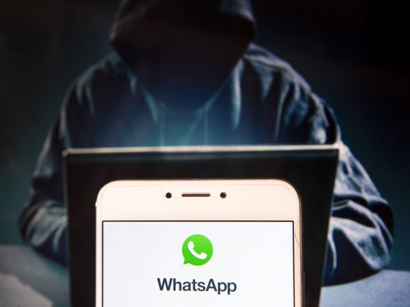 Hacker hinter WhatsApp Logo auf Handy
