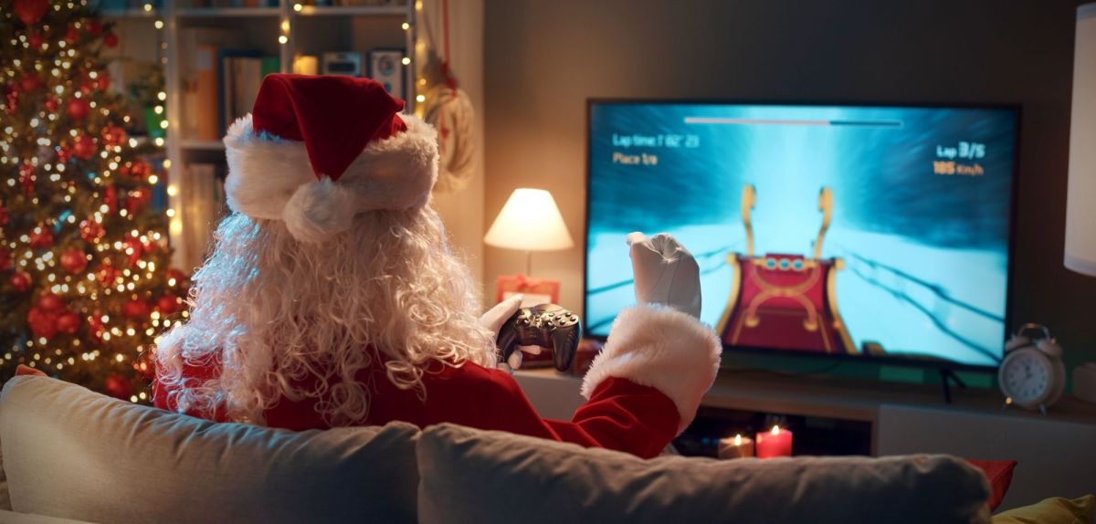Weihnachtsmann spielt vor einem Fernseher