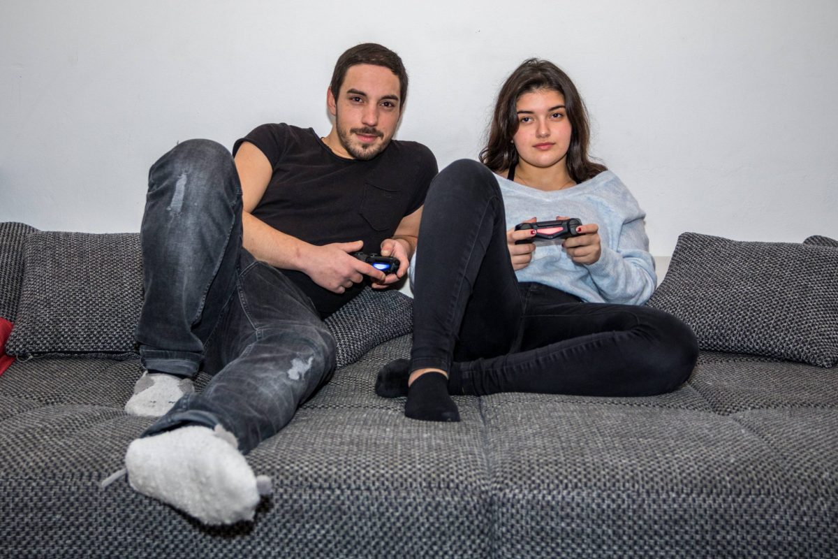 Mann und Frau mit PlayStation Controllern in der Hand auf Sofa