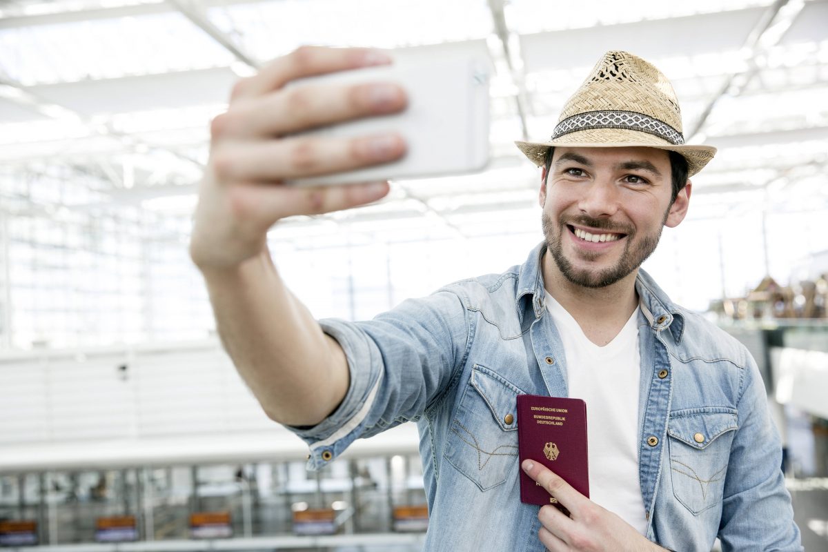 Mann hält Handy vor Gesicht mit Personalausweis in der Hand