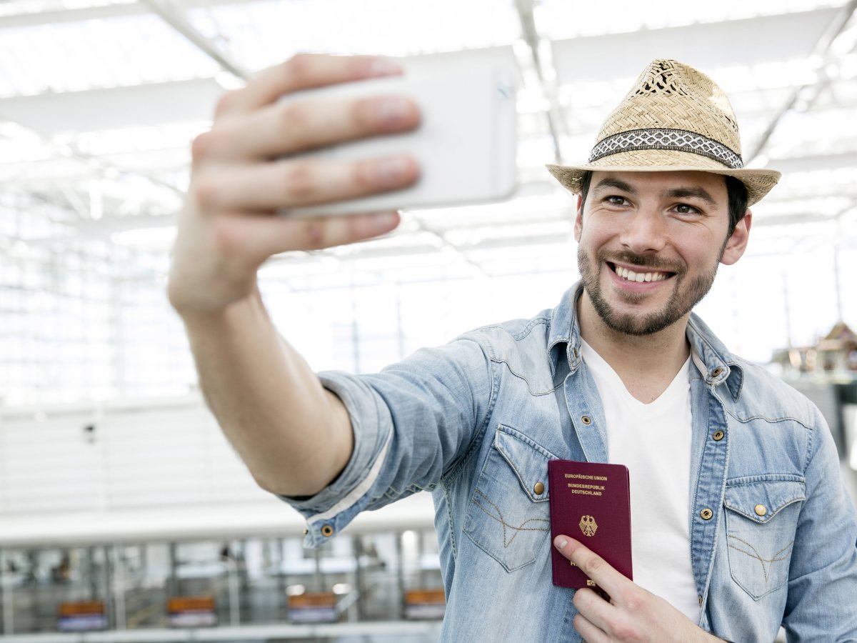 Mann hält Handy vor Gesicht mit Personalausweis in der Hand