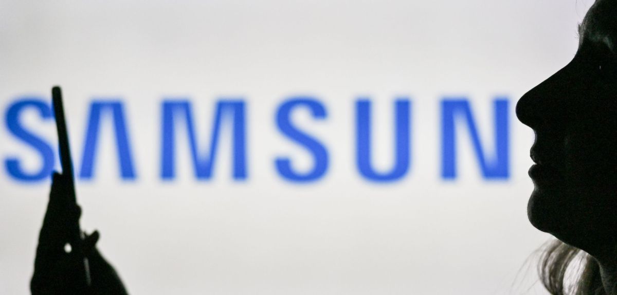 Frau mit Smartphone vor einem Samsung-Logo