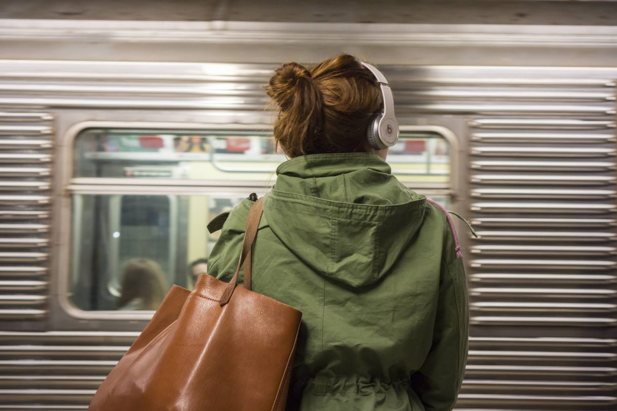 Frau mit Kopfhörern vor Bahn