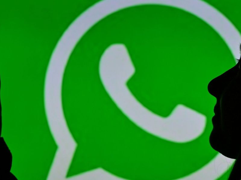 Frau mit Smartphone vor einem WhatsApp-Logo