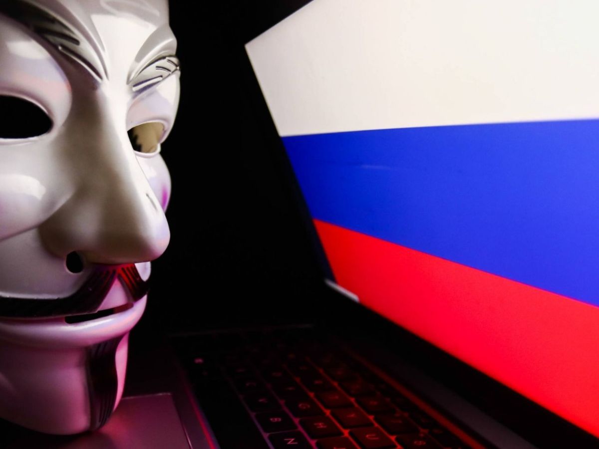Anonymous-Maske vor einem Laptop. mit Russland-Fahne.