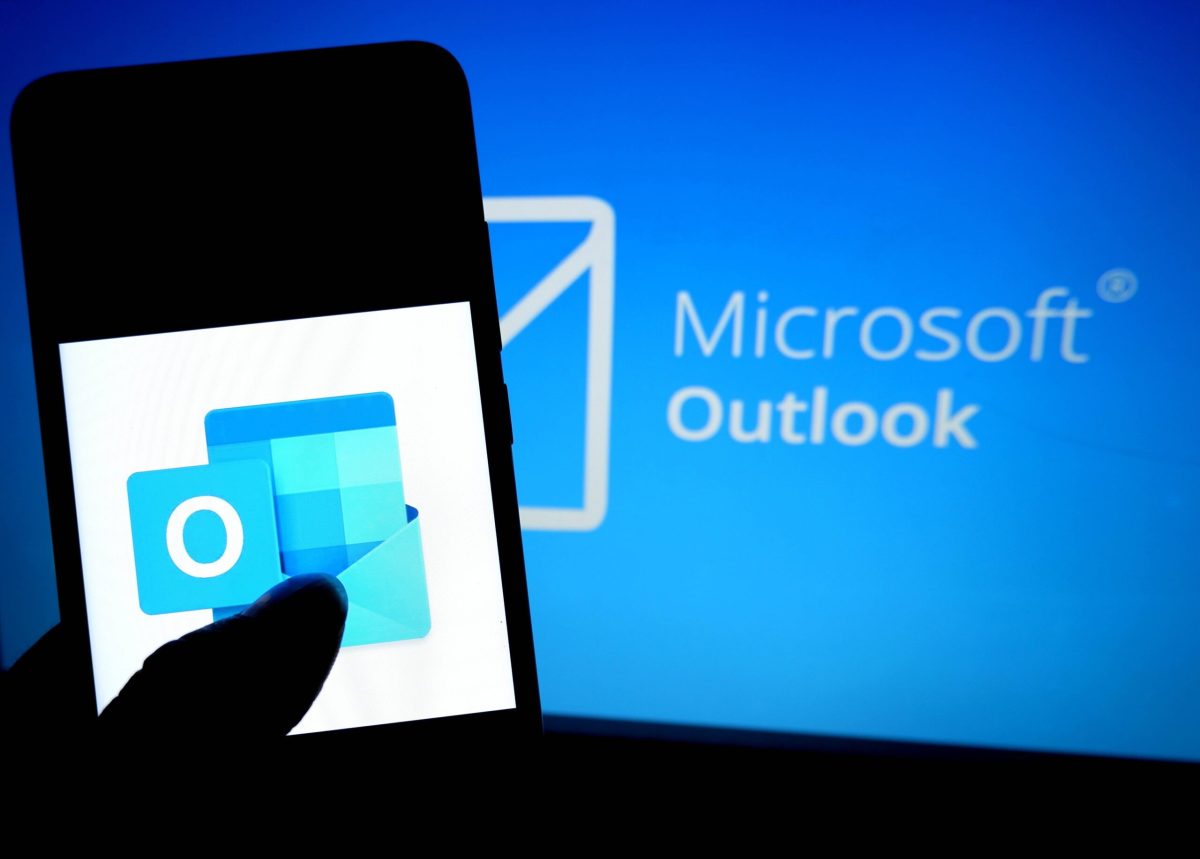 Handy mit Outlook App vor Bildschirm