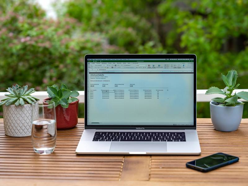 Laptop mit Excel auf Gartentisch im Freien