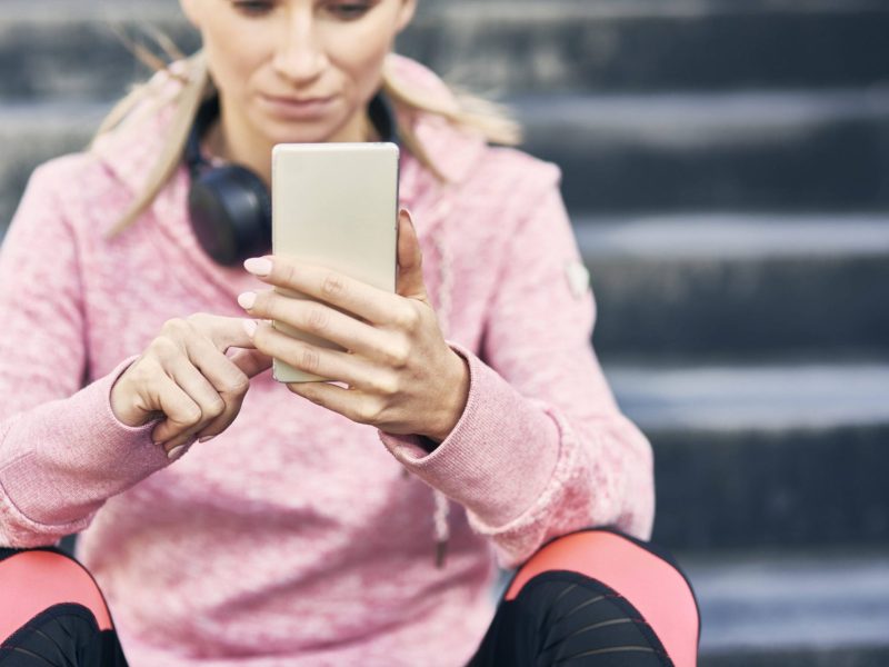 Frau schaut sitzend auf ihr Smartphone