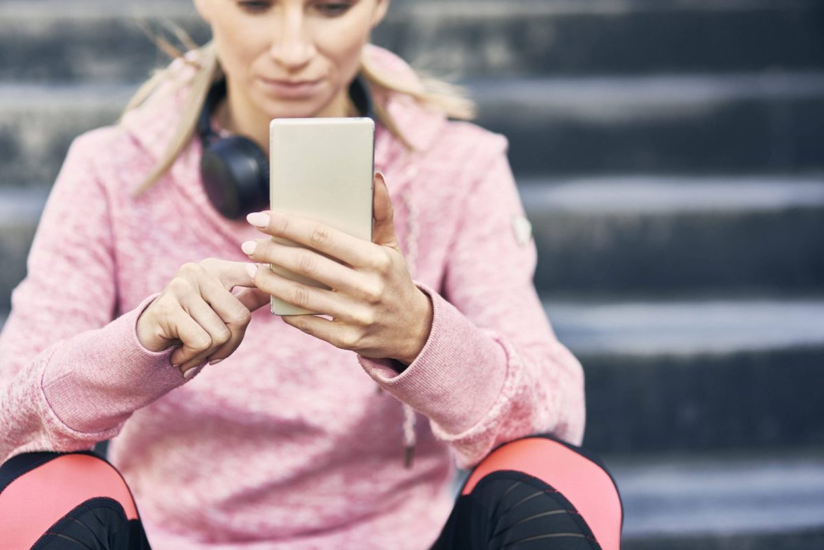 Frau schaut sitzend auf ihr Smartphone