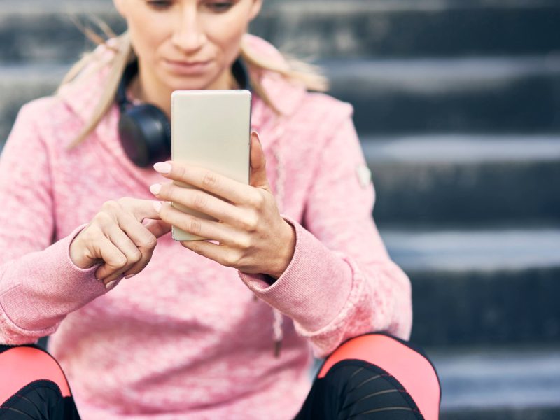 Frau schaut sitzend auf ihr Smartphone