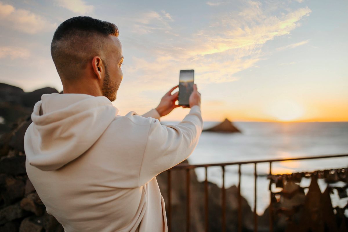 Mann nimmt Bild von Sonnenuntergang mit Handy auf