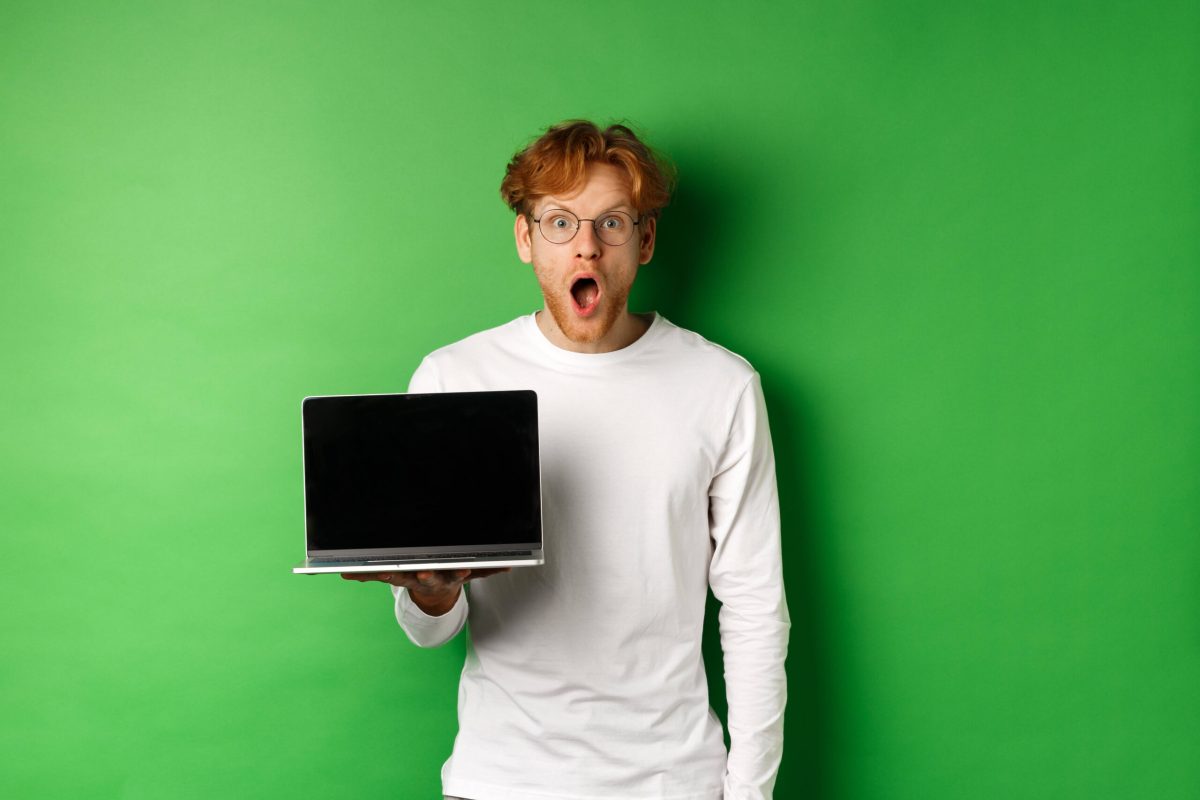 Mann steht mit Laptop vor Green Screen