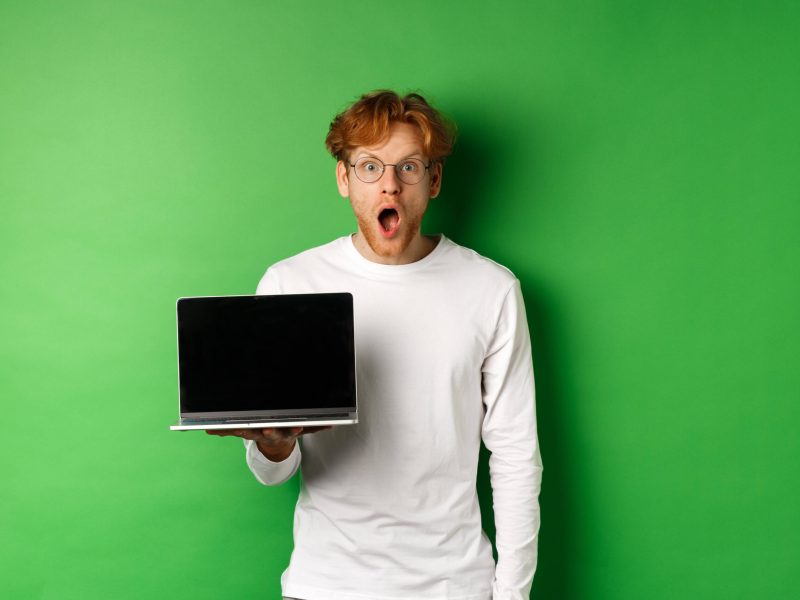 Mann steht mit Laptop vor Green Screen