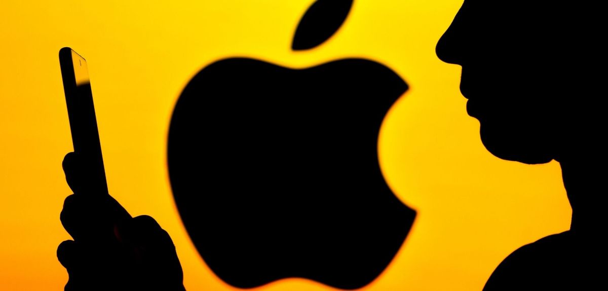 Frau mit iPhone vor Apple-Logo