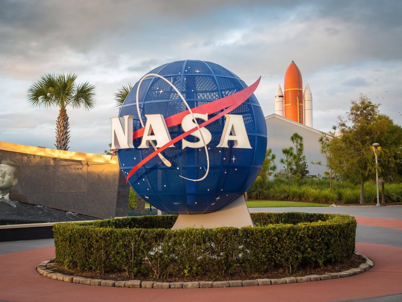 Logo der Nasa vor Kennedy Space Center, Weltraumbahnhof, hinten Rakete, Cape Canaveral, Merritt Island, Florida